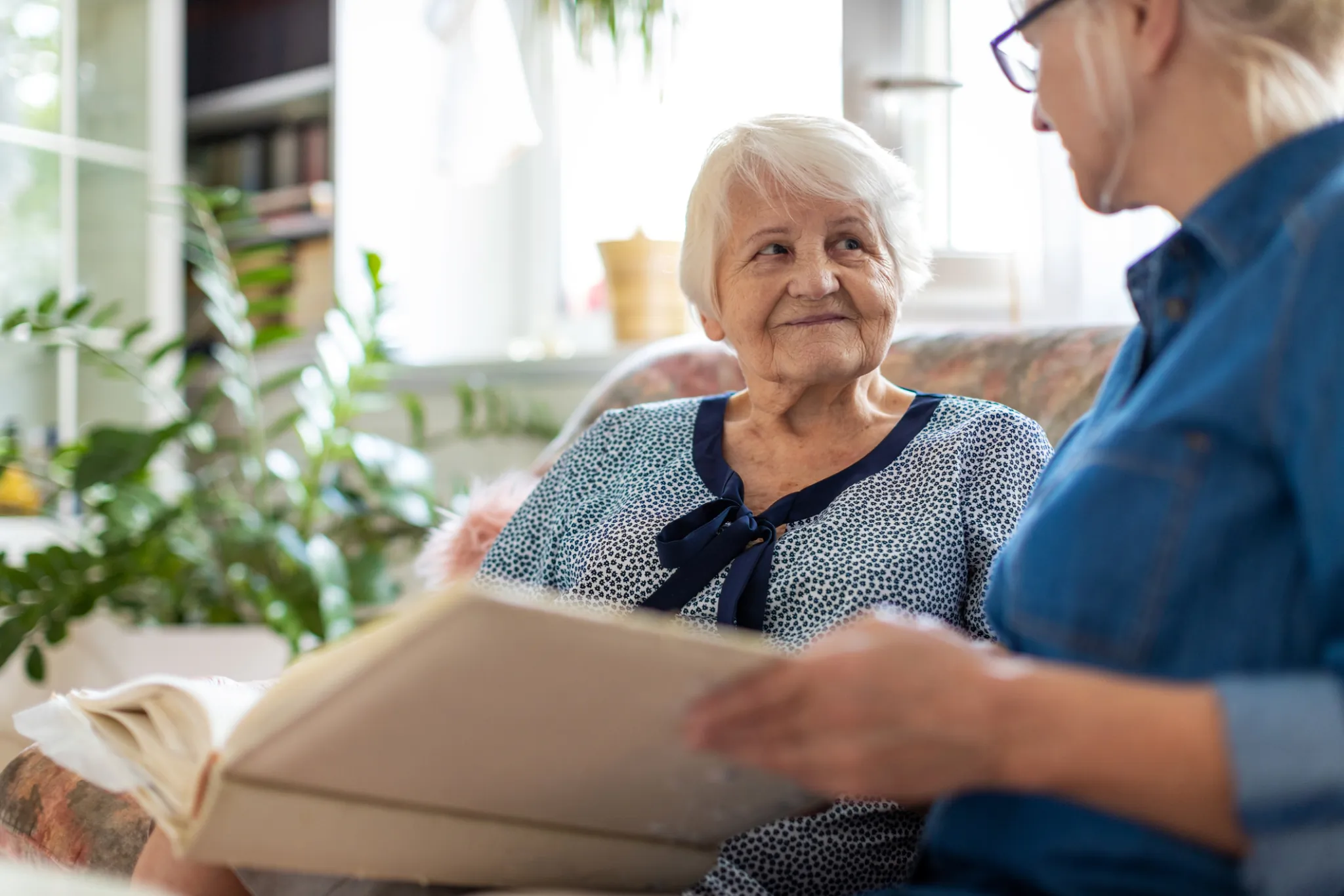 Senior woman looking at adult daughter with photo album